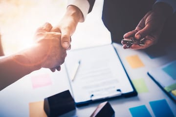 Two people shaking hands over a contract, symbolizing a successful business agreement