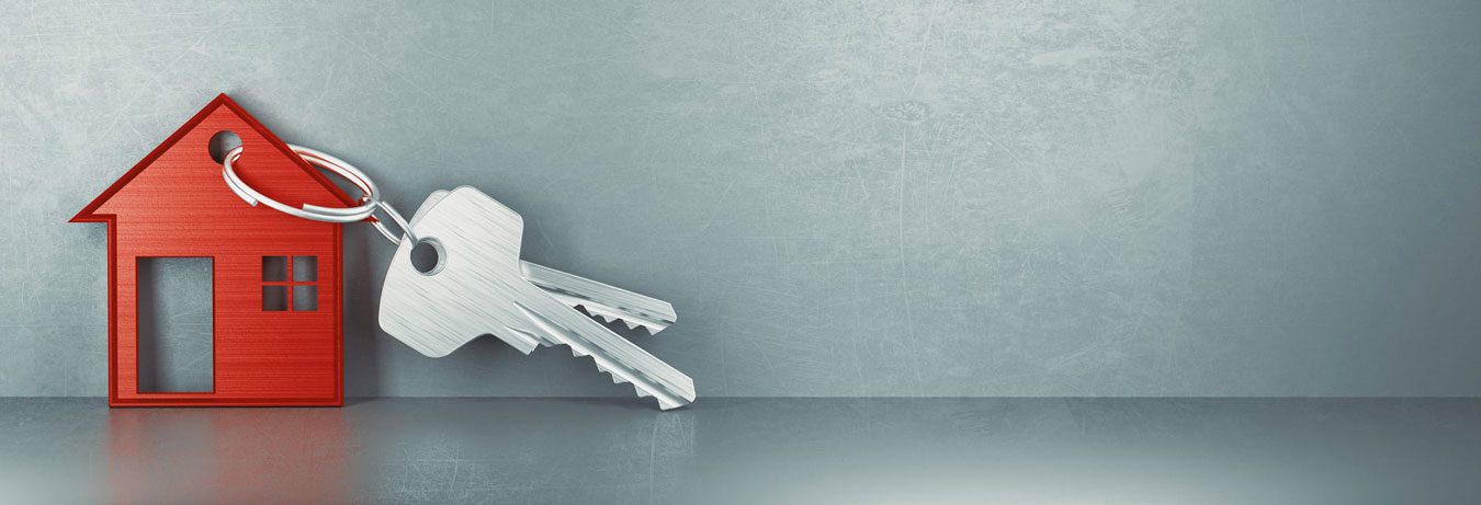 House-shaped keychain with a set of keys against a gray background