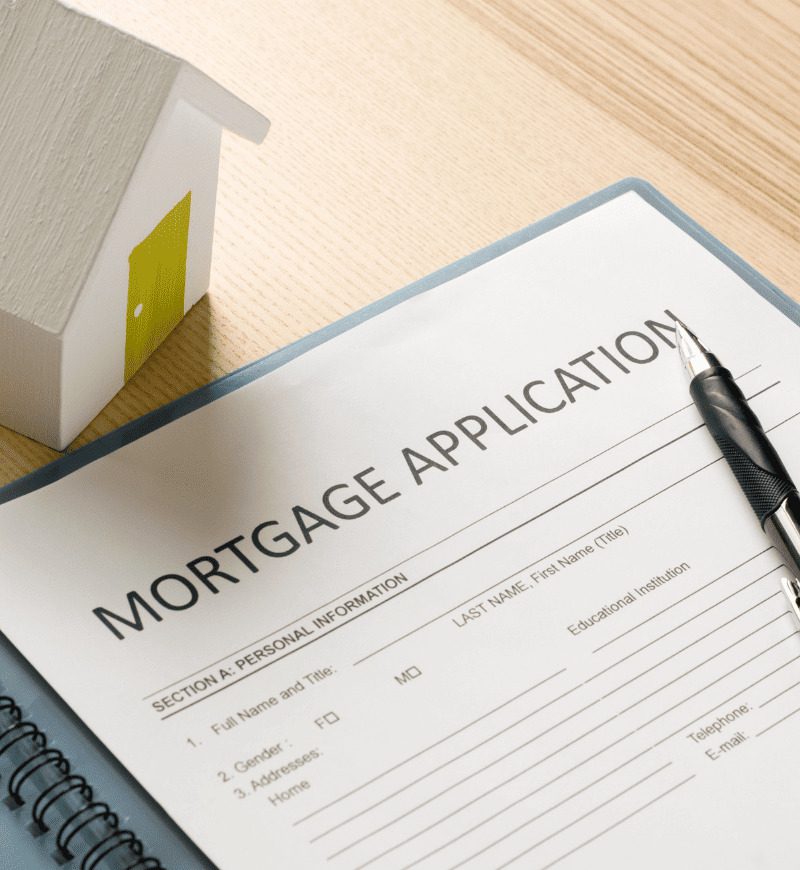 Mortgage application document with little wooden house model