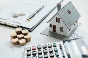 house model, money, pen and mortgage papers on table.