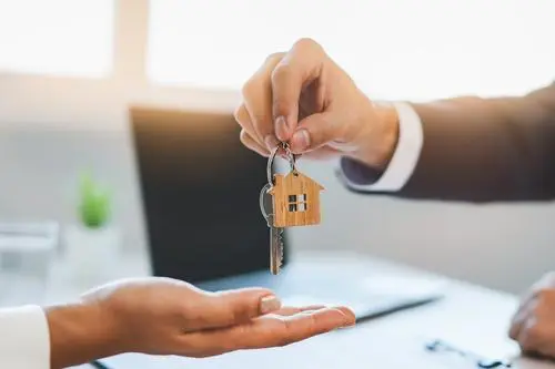 Person handing key to house, symbolizing home ownership. Image for Ace Mortgage Loan Corporation.
