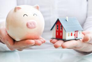 Hands holding a piggy bank and a house model - home financing concept