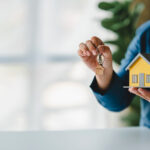 man holding house model - mortgage and loan concept
