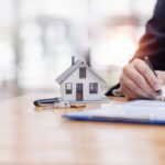 house model with business man signs a purchase contract or mortgage for buying a home
