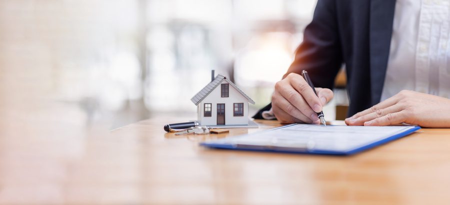 house model with business man signs a purchase contract or mortgage for buying a home